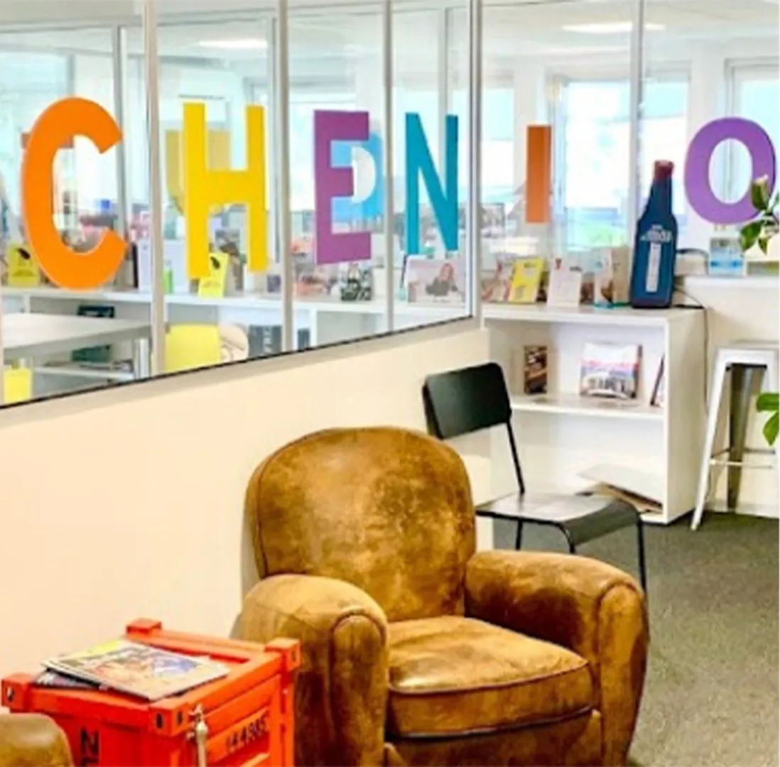 L’espace d’accueil de l’agence, avec un fauteuil club et des lettres colorées